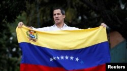 Venezuelan opposition leader Juan Guaido, who many nations have recognized as the country's rightful interim ruler, waves the Venezuelan flag at a gathering with supporters near Bolivia's embassy in Caracas, Venezuela, Nov. 16, 2019. 