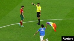 Un asistente salta al campo con un mensaje en su camiseta que reza "respeto a las mujeres iraníes" y una bandera de arcoíris, durante el Portugal-Uruguay del Grupo H del Mundial de Fútbol, en el estadio de Lusail, en Qatar, el 28 de noviembre de 2022.