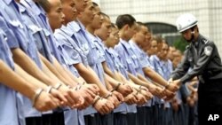 Guard checks handcuffs on group of prisoners in Chongqing (file photo)
