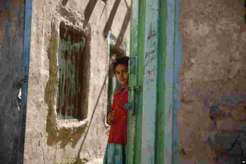 A girl stands in a doorway as she watches children receiving a polio vaccination, during a house-to-house polio immunization campaign in Sana&#39;a, Yemen.