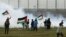 Protesters wave Palestinian flags amid teargas fired by Israeli troops near a fence on the Gaza Strip border with Israel, east of Gaza City, March 30, 2019.