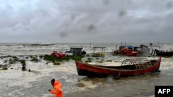 A man pulls a fishing boat to a sea shore as a preventive measure during rainfall in Kuakata on May 26, 2024, ahead of cyclone Remal's landfall in Bangladesh.