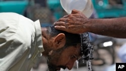 ARCHIVO - Un voluntario vierte agua para refrescar a un hombre durante un día caluroso en Karachi, Pakistán, el 21 de mayo de 2024. 