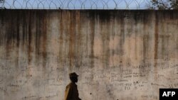 FILE - A prison guard walks along a perimeter wall at a prison in Rumbek, Lakes State, South Sudan, Feb. 19, 2014. 