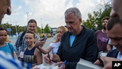 U.S. historian and author Timothy Snyder gives autographs on his books before a charity run to raise awareness of Ukrainian prisoners of war held by Russia, in Kyiv, Ukraine, on Sept. 14, 2024.