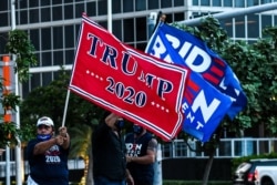 FILE - Supporters of U.S. President Donald Trump and Democratic presidential nominee and former Vice President Joe Biden wave flags at the Perez Art Museum in Miami, Florida, Oct. 5, 2020.