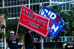 FILE - Supporters of U.S. President Donald Trump and Democratic presidential nominee and former Vice President Joe Biden wave flags of the Perez Art Museum in Miami, Florida, Oct. 5, 2020.
