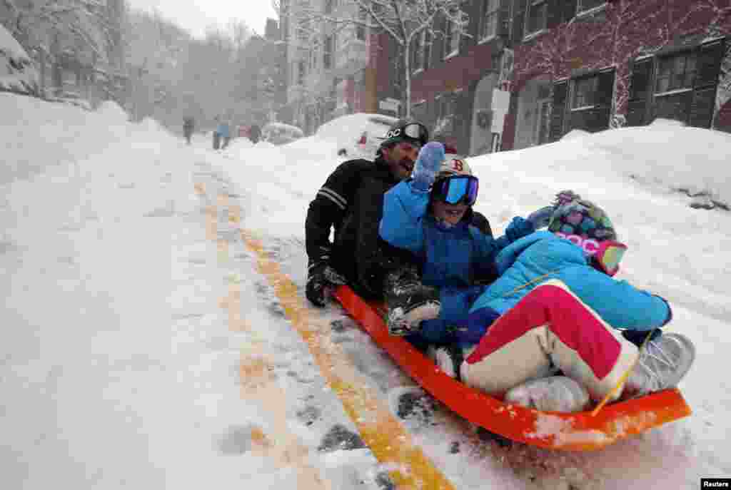 Peter Webster sleds down Chestnut Street with his children William (C) and Georgia (R) in Boston, Massachusetts February 9, 2013 during a winter blizzard. REUTERS/Brian Snyder (UNITED STATES - Tags: ENVIRONMENT) - RTR3DJDO