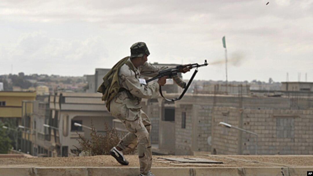 A Libyan revolutionary fighter fires his machine gun while attacking pro-Gadhafi forces on the western side of Sirte, Libya, October 13, 2011.