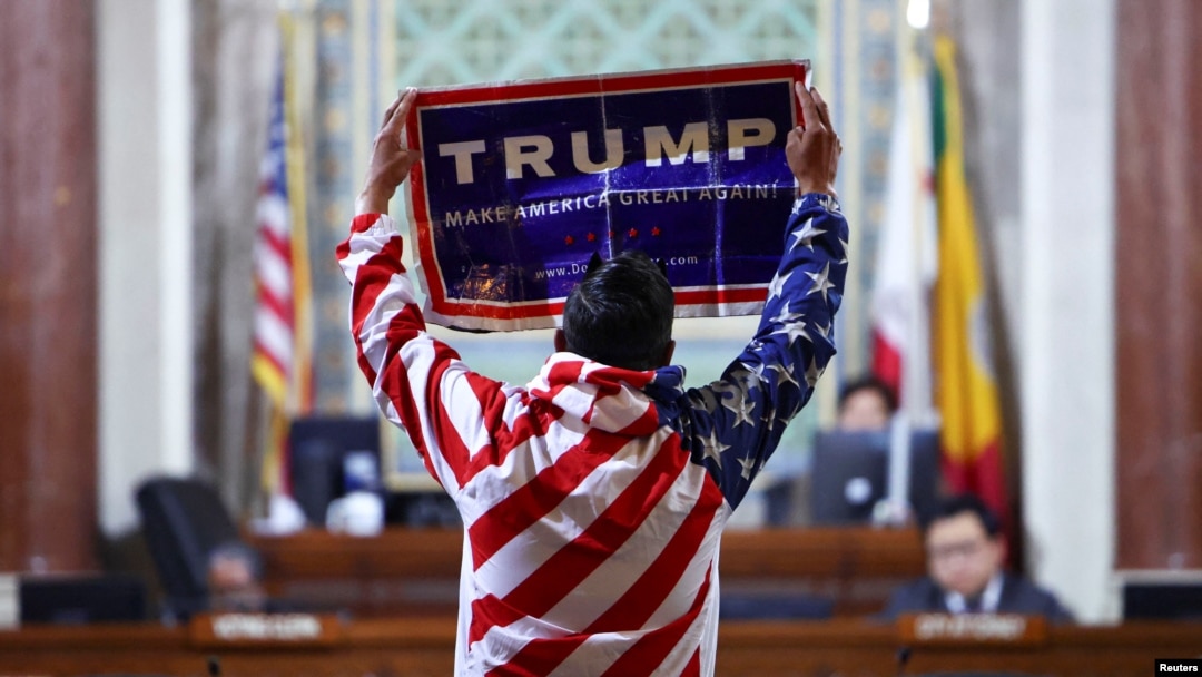 FILE - protester holds a Trump sign at City Hall as the Los Angeles City Council meets to consider adopting a "Sanctuary City'' ordinance in Los Angeles, California, November 19, 2024. 