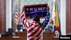 FILE - protester holds a Trump sign at City Hall as the Los Angeles City Council meets to consider adopting a "Sanctuary City'' ordinance in Los Angeles, California, November 19, 2024. 