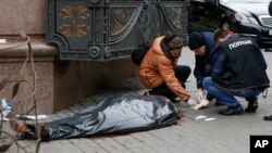 Forensic experts and police officers investigate at the scene following the killing of Denis Voronenkov in Kyiv, Ukraine, March 23, 2017. 