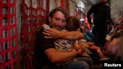 A father hugs his son as Greek and Greek Cypriot nationals are evacuated from Lebanon on a Hellenic Air Force C130, due to ongoing hostilities between Hezbollah and the Israeli forces, in Beirut, Lebanon.