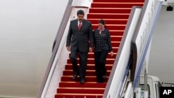 ARCHIVO - El presidente de Venezuela, Nicolás Maduro, y la primera dama Cilia Flores bajan por las escalinatas del avión a su servicio en el Aeropuerto Internacional de Beijing, China, el 1 de septiembre de 2015.