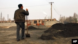 A villager looks towards a rare earth smelting plant as he takes a break from shoveling cast-off tailings of crushed mineral ore that contain rare earth metals in Xinguang Village, (File)