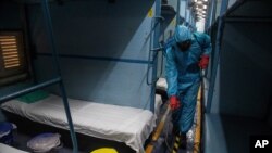 A health worker in personal protective equipment sanitizes a compartment of a train prepared as a COVID-19 care center in the wake of spike in the number of coronavirus cases, at a railway station in Gauhati, India, May 6, 2021.