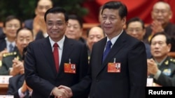 China's President Xi Jinping shakes hands with China's newly elected Premier Li Keqiang (L) as other delegates clap during the fifth plenary meeting of the first session of the 12th National People's Congress (NPC) in Beijing, March 15, 2013.