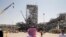 FILE - In this Sept. 20, 2019 file photo, taken during a trip organized by the Saudi information ministry, a man stands in front of the Khurais oil field in Khurais, Saudi Arabia, after it was hit during a Sept. 14 attack. 