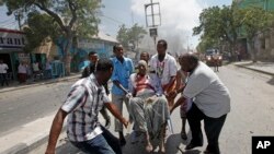 Sekouris kap pote yon nonm ki te blese nan yon atak ak bonm kote yon kòmando suisid te itilize yon machin pyeje pou l te touye plizyè moun nan Mogadisio, Somali Lendi 13 mas 2017 la. (Foto: AP/Farah Abdi Warsameh)