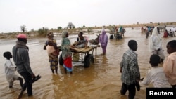 FILE - Displaced people carry their belongings to relocate to dryer areas following flooding caused by heavy rains, Nyala, Sudan, June 3, 2017. Parts of the country have been reeling from fresh floods over the past two months.