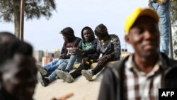 Des journaliers migrants africains à la recherche de petits emplois attendent sous un pont dans la capitale libyenne Tripoli pour être embauchés par des employeurs potentiels, le 6 mars 2021.