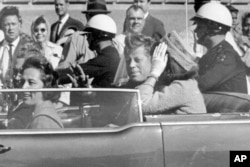 FILE - President John F. Kennedy waves from his car in a motorcade in Dallas, Texas, with first lady Jacqueline Kennedy, right, Nellie Connally, second from left, and her husband, Texas Gov. John Connally, far left, Nov. 22, 1963.