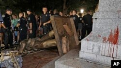 FILE - police stand guard after the confederate statue known as Silent Sam was toppled by protesters on campus at the University of North Carolina in Chapel Hill, N.C.