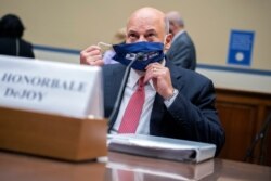 FILE - Postmaster General Louis DeJoy removes his face mask as he arrives to testify before a House Oversight and Reform Committee hearing on the Postal Service on Capitol Hill, August 24, 2020, in Washington.