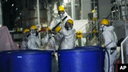FILE - Men in hazmat suits work inside a facility with equipment to remove radioactive materials from contaminated water at the Fukushima Daiichi nuclear power plant, run by Tokyo Electric Power Company Holdings (TEPCO), in Okuma town, northeastern Japan, Thursday, March 3, 2022.