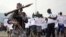 A Burundian soldier walks infront of residents during a demonstration against the Rwandan government in Burundi's capital Bujumbura, Feb. 20, 2016. 