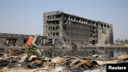 A People's Liberation Army soldier of its anti-chemical warfare corps in a protection suit sprays a liquid on debris at the site of last week's blasts in Tianjin, China, Aug. 21, 2015.