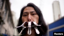 Brother Nut, a Chinese performance artist with three metallic clips sealing his mouth, poses for a picture in Shanghai.