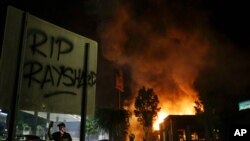 "RIP Rayshard" is spray painted on a sign as as flames engulf a Wendy's restaurant during protests Saturday, June 13, 2020, in Atlanta. The restaurant was where Rayshard Brooks was shot and killed by police Friday evening following a struggle in the…