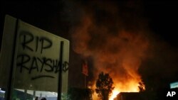 "RIP Rayshard" is spray painted on a sign as as flames engulf a Wendy's restaurant during protests, June 13, 2020, in Atlanta. 