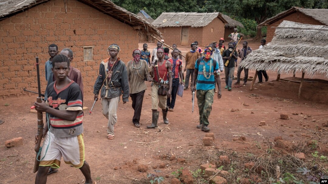 FILE - Anti-Balaka combatants patrol in the parish of Gambo, southeastern Central African Republic, Aug. 16, 2017.