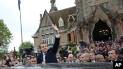 Emmanuel Macron, center, waves as he leaves the polling station after casting his ballot in the presidential runoff election in Le Touquet, France, May 7, 2017.