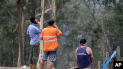 Residents on edge of Batemans Bay, Australia, relax after a fire threat near their homes eased Saturday, Jan. 4, 2020.
