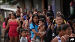 ARCHIVO - La migrante venezolana Minorca Parra sostiene a su hija Karin Alvear mientras hace fila para recibir alimentos en un campamento temporal después de cruzar el Tapón del Darién desde Colombia en Lajas Blancas, Panamá, el 27 de junio de 2024. 