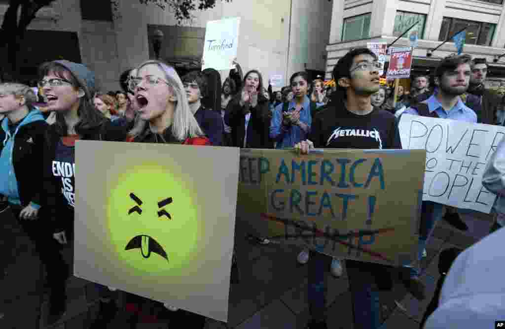 Protesters hold signs during a protest against the election of President-elect Donald Trump, Nov. 9, 2016, in downtown Seattle.