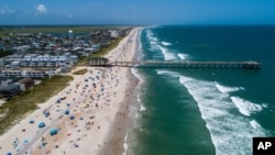 Bañistas en la playa de Wrightsville, Carolina del Norte, el domingo 2 de agosto de 2020 mientras la tormenta tropical Isaías avanza por la costa sureste del país. (Travis Long/The News & Observer) 