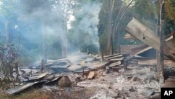 FILE - Smoke rises from debris and corrugated roofing of a school building that was burned to the ground in Taung Myint village in the Magway region of Myanmar on Oct. 16, 2022.