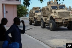 Kenyan police officers, part of a U.N.-backed multinational force, drive past residents in armored vehicles on the streets of Port-au-Prince, Haiti, Sept. 4, 2024.