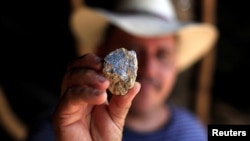 FILE - A miner shows a stone with gold mineral at San Sebastian mine in Santa Rosa de Lima, El Salvador, April 26, 2017. 