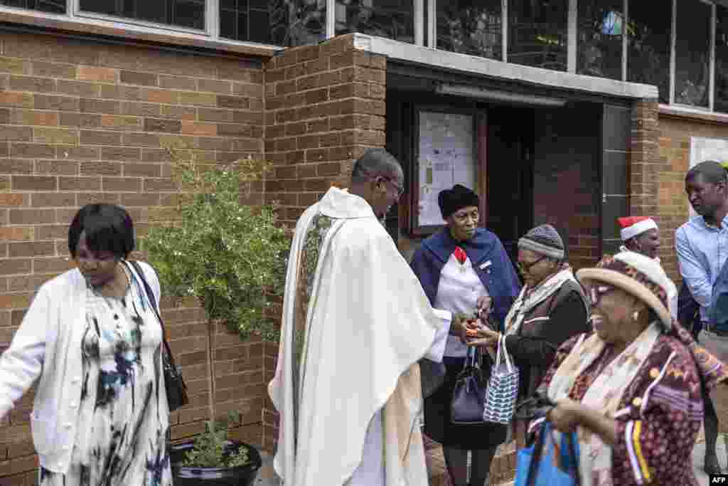 Parish priest of Regina Mundi Church, Fr Nqobile Mzolo OMI (2nd L) gives gifts to parishioners at the end of the Christmas Mass at Regina Mundi Church in Soweto, South Africa, Dec. 25, 2024.