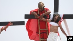 A volunteer dressed as a Roman centurion unties Ruben Enaje's wrist after he was nailed to a wooden cross during a Good Friday re-enactment in Cutud, Pampagna province, northern Philippines, March 25, 2016.