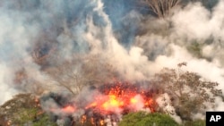 This May 16, 2018, image provided by the U.S. Geological Survey shows lava spattering from an area between active Fissures 16 and 20 photographed on the lower east rift of the Kilauea volcano, near Pahoa, Hawaii. 