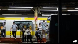 Orang-orang yang mengenakan masker menunggu kereta api yang mendekat di sebuah stasiun di Tokyo, Kamis, 9 September 2021. (Foto: AP/Hiro Komae)