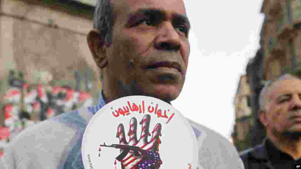 An activist holds a sign with an anti-terrorism picture and Arabic that reads &quot;terrorists brotherhood&quot; during an anti-terrorism demonstration in Cairo, Dec. 26, 2013. 