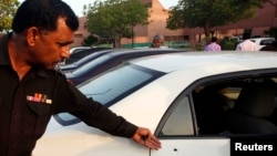 A policeman points out bullet hole in car belonging to journalist Hamid Mir in Karachi, Apr. 19, 2014.