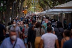 FILE - People wearing face masks walk along a boulevard in Barcelona, Spain, Aug. 30, 2020.